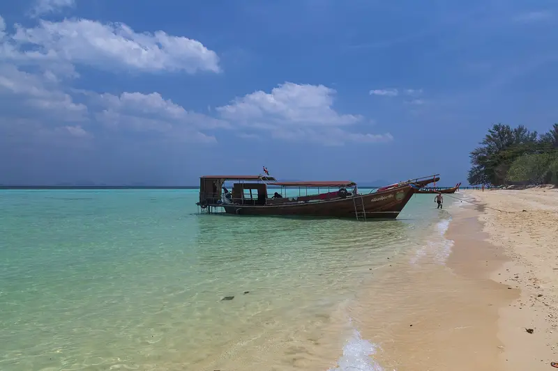 A longtail boat moored off the white-sand beach of Ko Kradan, Trang